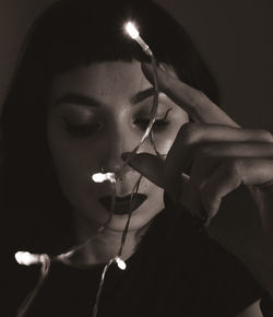 Close-up portrait of young woman holding lights in hands