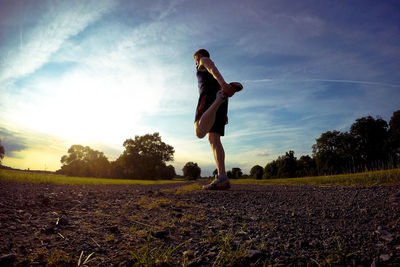 Full length of man exercising on road during sunset