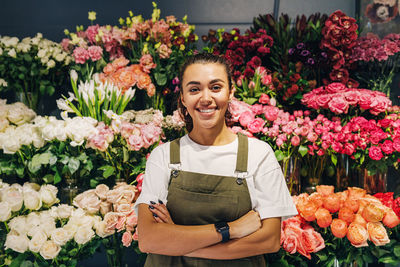 Portrait of smiling female florist standing against flowers in shop