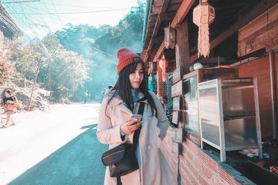 Woman standing on mobile phone in city