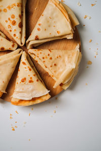 Delicious crepes laid out in triangles in a circle on a wooden board, flat lay	
