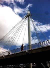 Low angle view of suspension bridge against cloudy sky