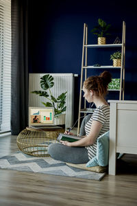 Woman sitting on potted plant at home