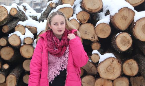 Portrait of woman standing against logs