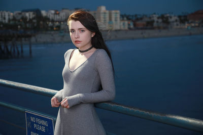 Portrait of young woman standing against sea