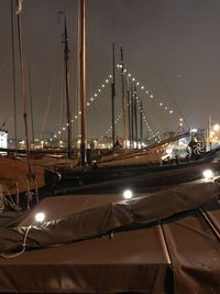 Sailboats moored at harbor against sky at night