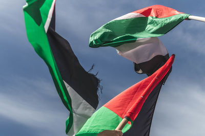 Low angle view of palestinian flags against blue sky