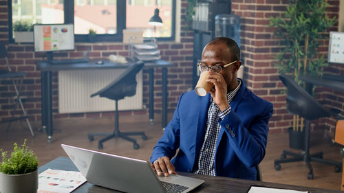 Young man using mobile phone while sitting on table