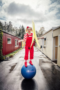 Portrait of smiling woman standing on fitness ball