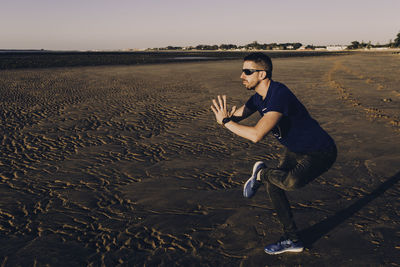 Young man practicing yoga at beach