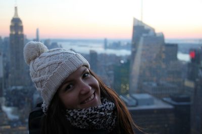 Portrait of smiling woman against cityscape during sunset