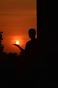 Silhouette man against orange sky