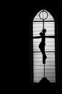 Silhouette woman standing by window