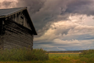 Low angle view of abandoned house against cloudy sky