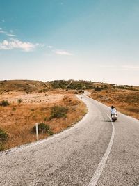 Rear view of man walking on road against sky