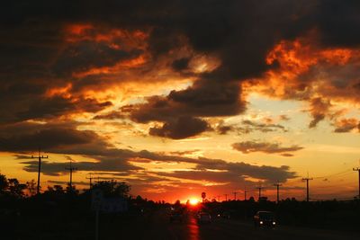 Silhouette city against dramatic sky during sunset