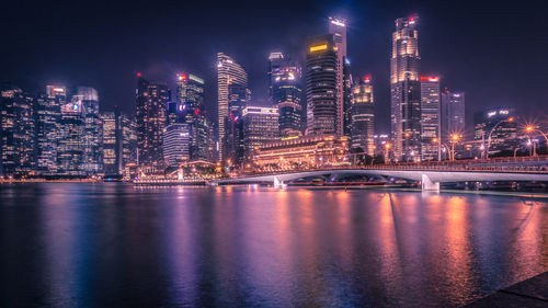 Illuminated city by buildings against sky at night