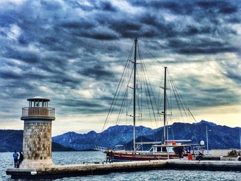 Boats moored in sea against cloudy sky