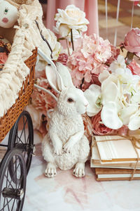 A white porcelain hare next to a brown wicker stroller, books in light pink wrapping paper