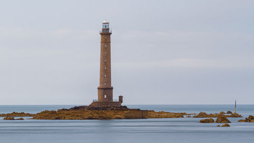 Lighthouse by sea against sky