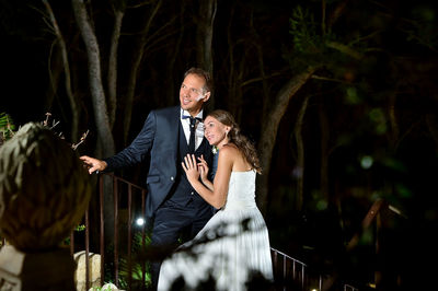 Wedding couple standing by railing at night