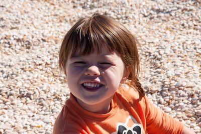Close-up portrait of cute smiling girl at beach during sunny day