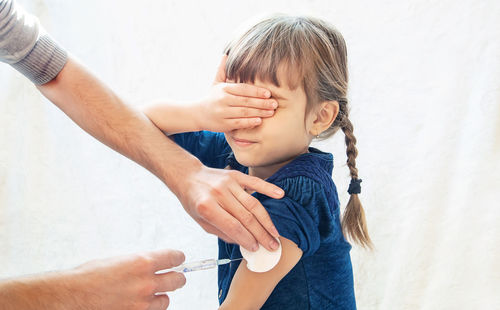 Hands giving vaccination to girl