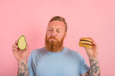 Midsection of man holding strawberry against white background