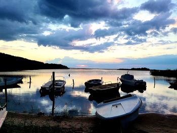 Boats moored on lake against sky during sunset