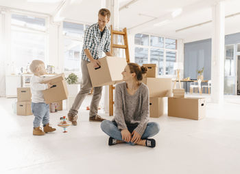 Happy family moving into new home with father and daughter carrying cardboard boxes