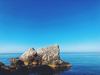 Rock formation in sea against blue sky