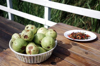 A close-up of a basket of naturally grown guava on a wooden table, harvested in garden