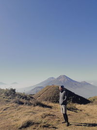 Full length of man standing on mountain against clear sky