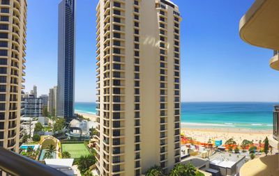 Modern buildings by sea against clear blue sky