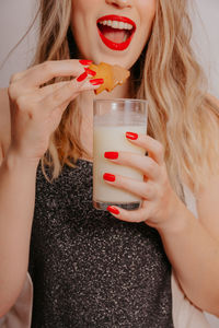 Midsection of woman eating cookies with milk