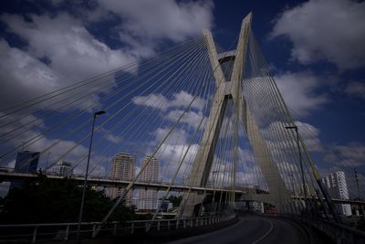 Low angle view of suspension bridge against cloudy sky