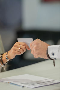 Cropped hand of man giving placard to woman in office