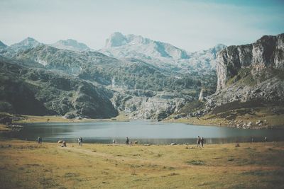 People standing lake and mountains against sky