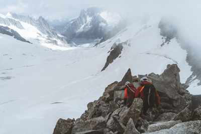 Roped party on rocky ridge above glacier with sun rays