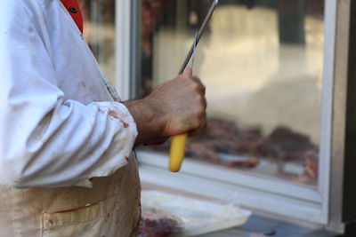 Midsection of butcher preparing food in kitchen