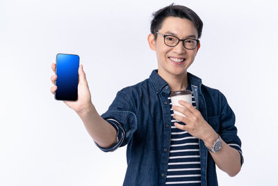 Portrait of smiling young man using smart phone against white background