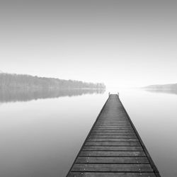 Pier over lake against clear sky