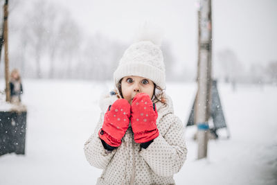 Portrait of smiling young woman standing on snow