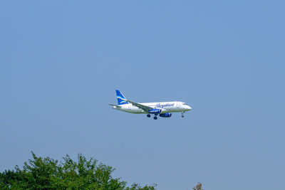 Low angle view of airplane flying against clear blue sky