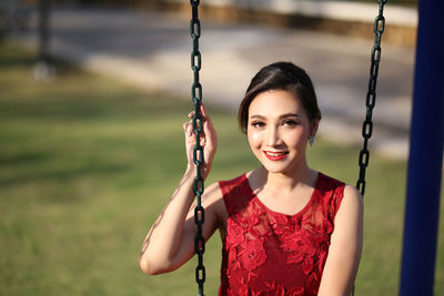 Portrait of smiling woman on swing in playground