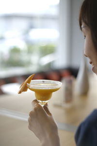 Cropped image of woman having mango smoothie at cafe