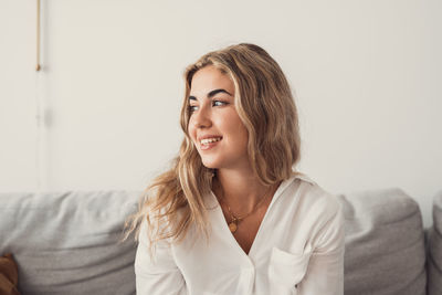 Young woman looking away against wall