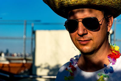 Close-up portrait of man smoking while wearing artificial flowers