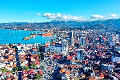 High angle view of city by sea and buildings against sky