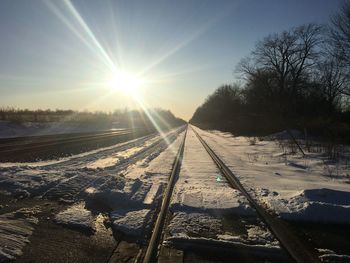 Snow covered railroad tracks against sky during winter